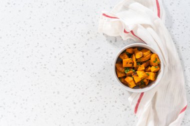 Düz yatıyordu. Beyaz seramik bir kasede fırında tatlı patates servis ediyorum..