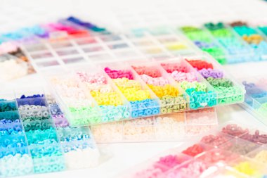 Beyaz bir masaya yerleştirilmiş çeşitli kil boncuk kutuları yaratıcı çocukların el sanatları projesini bekliyor..