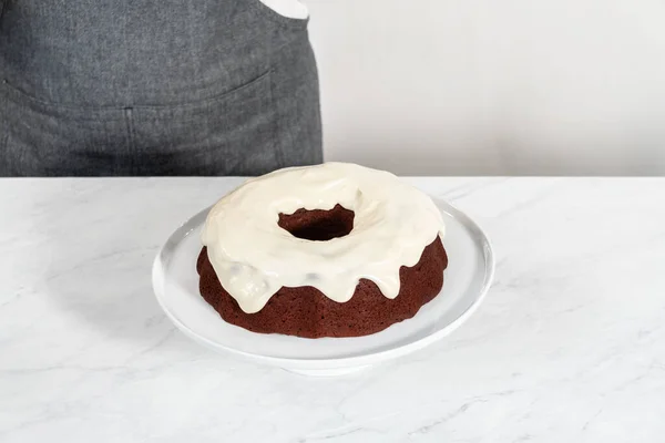Decorating red velvet bundt cake with chocolate lips and hearts over cream cheese glaze.
