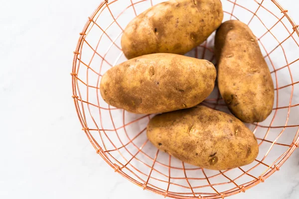 Pressure Cooker Baked Potatoes. Raw potatoes in a wire basket on the kitchen counter.