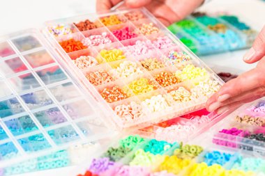 Beyaz bir masaya yerleştirilmiş çeşitli kil boncuk kutuları yaratıcı çocukların el sanatları projesini bekliyor..