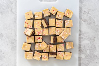 Düz yatıyordu. Büyük bir mutfak bıçağıyla şeker kamışı şekerlemesini beyaz bir kesme tahtasında kare parçalara ayırmak..