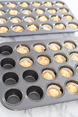 Scooping cupcake batter with dough scoop into a baking pan with liners to bake American flag mini cupcakes.
