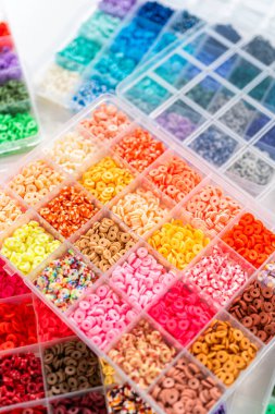 Beyaz bir masaya yerleştirilmiş çeşitli kil boncuk kutuları yaratıcı çocukların el sanatları projesini bekliyor..