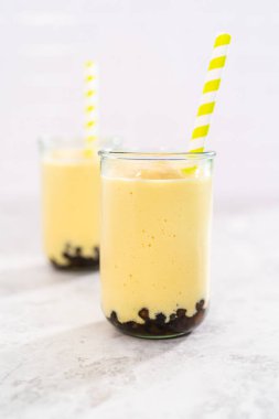 Taze yapılmış mango boba smoothie. Kağıt kamışla içme bardağında..