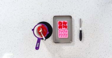 Flat lay. Filling bow silicone chocolate mold with melted chocolate to make a chocolate pretzel Christmas wreath.