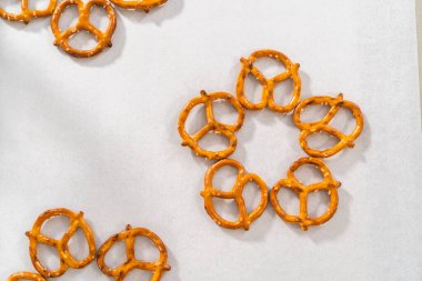 Dipping pretzels twists into melted chocolate to make a chocolate pretzel Christmas wreath.