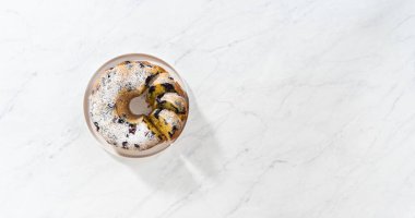 Düz yatıyordu. Taze pişmiş limonlu yaban mersinli kek dilimliyorum. Pudra şekerli..