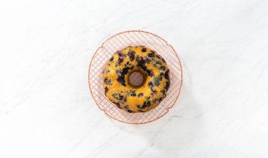 Düz yatıyordu. Soğutulmuş taze pişmiş limonlu yaban mersinli keki soğutucu rafından servis tabağına aktarıyorum..