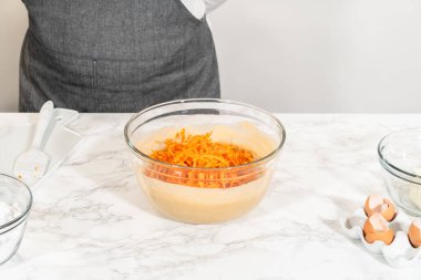 Büyük bir cam kasede, malzemeler harika havuçlu kek pişirmek için ustalıkla karıştırılır..