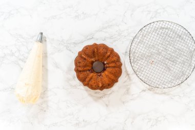 Düz yatıyordu. Hassasiyetle, Beyaz Çikolatalı Ahudududulu Çörek dikkatlice tavadan çıkartılır. Lezzetli krem peynirli kremayla süslenir ve lezzetli bir ziyafet yaratır..