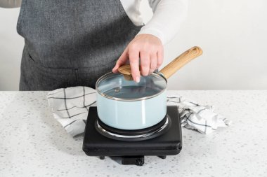 Boiling water in a cooking pot to prepare chocolate pistachio fudge.