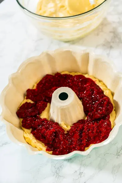 After greasing the bundt cake pan, its time to fill it with the prepared cake batter and delightful raspberry cake filling - creating a perfect harmony of flavors.