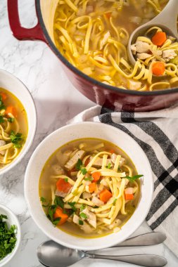 Beyaz seramik çorba kaselerinde kluski şehriyeli tavuk çorbası servis ediyorum..