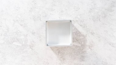 Düz yatıyordu. Kızılcık fıstıklı şekerleme hazırlamak için kare peynirli kek tavasını parşömen kağıdıyla kaplamak.