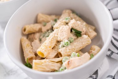 Küçük bir kasede yeşil bezelyeli tavuk ve rigatoni makarna..