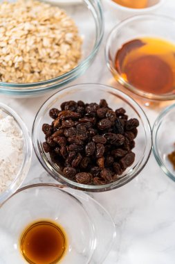 Yumuşak yulaf ezmesi üzümlü cevizli kurabiye pişirmek için cam karışımında ölçülmüş malzemeler..