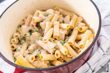 Alfredo soslu tavuk pişirmek için mayalı bir fırının içindekileri karıştırıyorum..