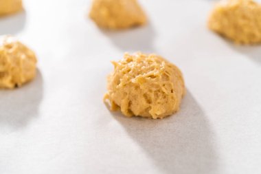 Kurabiye hamuru kepçesiyle kurabiye hamuru pişirip parşömen kağıdıyla kaplanmış bir tepsiye koyup muzlu kurabiyeleri çikolatalı çiselemek..