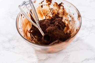 Scooping cookie dough with dough scoop into a baking sheet lined with parchment paper to bake chocolate cookies with chocolate hearts for Valentines Day.