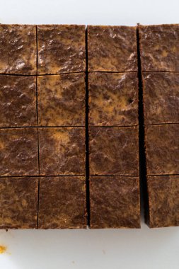 Çikolatalı fıstık ezmeli şekerlemeyi beyaz bir kesme tahtasında küçük parçalara ayırmak..