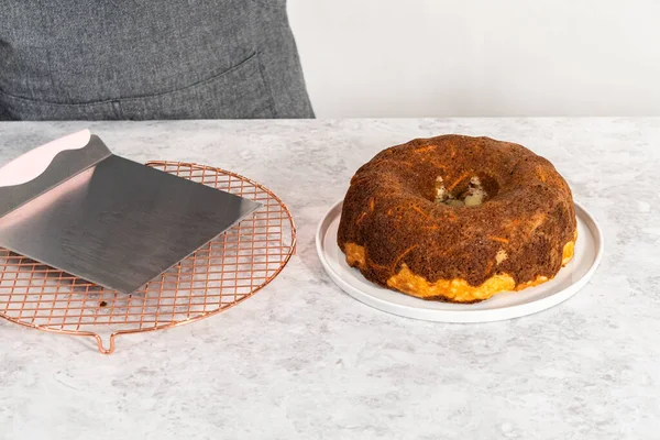 将新鲜烤胡萝卜面包从圆形冷却架上转移到盘子上 — 图库照片