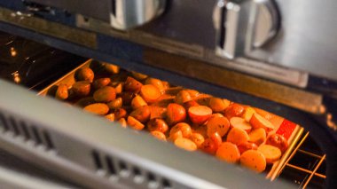 Modern bir mutfak ortamında, genç bir adam şu anda fırında baharatlı gökkuşağı patatesi kızartılarak lezzetli bir yemeğe doğru önemli bir adım atıyor..