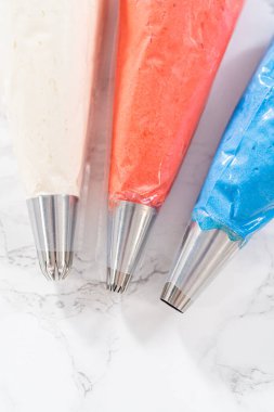 Amerikan bayrağı mini keklerini süslemek için metal uçlu boru torbalarının içinde tereyağlı krema..