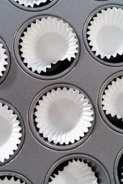 Scooping cupcake batter with dough scoop into a baking pan with liners to bake American flag mini cupcakes.