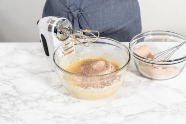 Büyük bir bardakta ıslak malzemeler karıştırarak kırmızı kadife kekler ve beyaz çikolatalı ganache kreması pişiriyorum..