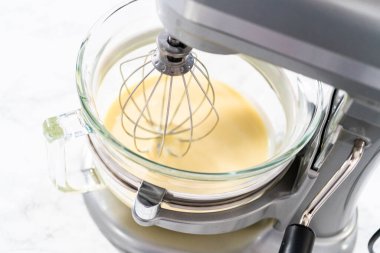 Beyaz çikolatalı ganache yapmak için mutfak mikserinde beyaz ganache çırpmak..