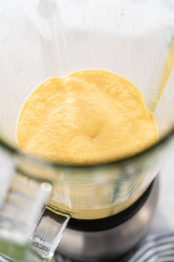 Mutfak blendırında mango boba smoothie hazırlamak için malzemeler karıştırılıyor.