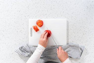 Düz yatıyordu. Kırmızı elmaları beyaz bir kesme tahtasının üzerinde ince dilimlere ayırmak.