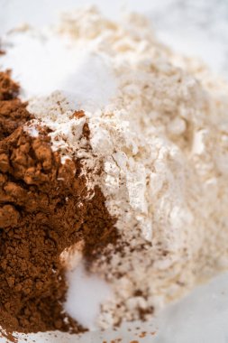 Büyük bir bardakta ıslak malzemeler karıştırarak kırmızı kadife kekler ve beyaz çikolatalı ganache kreması pişiriyorum..