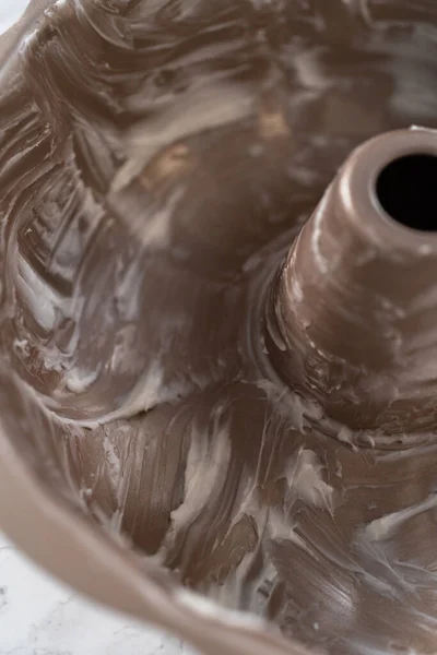 stock image Greasing metal bundt cake pan to bake eggnog bundt cake.