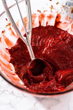 Kek hamurunu hamur kepçesiyle kek tepsisine doldurmak folyo kaplamalarla kaplanmış beyaz çikolatalı ganache kremalı kırmızı kadife kekler pişirmek.