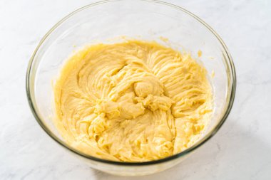 Limonlu yaban mersinli kek yapmak için büyük bir bardakta karıştırma malzemesi..