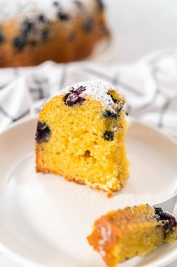 Taze pişmiş limonlu yaban mersinli kek dilimliyorum. Pudra şekerli..