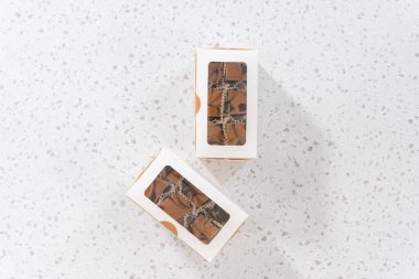 Düz yatıyordu. Fıstık ezmeli ev yapımı çikolatalı şekerlemeler beyaz bir hediye kutusuna konuyor..