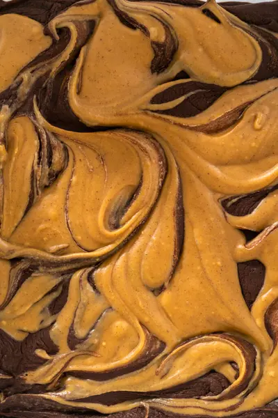 Removing chocolate fudge with peanut butter swirl from the baking pan lined with parchment