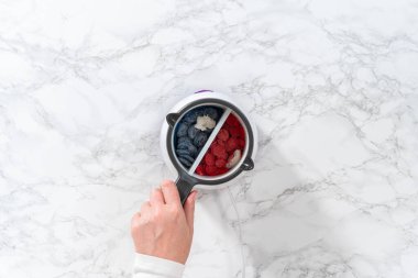 Düz yatıyordu. Çikolata parçalarını eritip, eriyip, kırmızı, beyaz ve mavi çubuk kraker yapıyorlar..