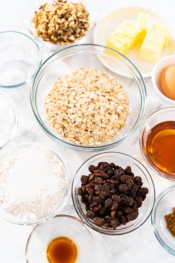Yumuşak yulaf ezmesi üzümlü cevizli kurabiye pişirmek için cam karışımında ölçülmüş malzemeler..