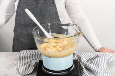 Eriyen beyaz çikolata parçacıkları ve diğer malzemeler kaynamış suyun üzerinde karışıp kızılcık fıstıklı şekerleme hazırlıyor..