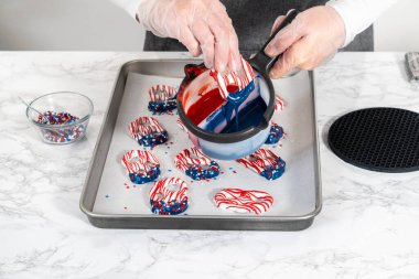 Flat lay. Dipping pretzels twists into melted chocolate to make red, white, and blue chocolate-covered pretzel twists.