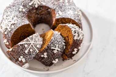 Dilimlenmiş zencefilli kek karamel dolgulu, kremalı pasta ve kek tabağında toz şeker..