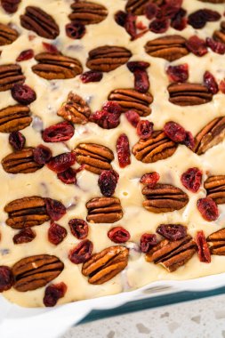 Beyaz çikolatalı fındıklı fındıklı çikolatalı şekerlemeyi hazırlamak için parşömen kağıdıyla kaplanmış fırın tavasına şekerleme döküyorum..