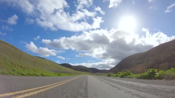 车辆在明亮的阳光下沿着宽山路巡航 周围的风景被灿烂的阳光照亮了 当汽车行驶时 形成了一幅风景如画的迷人景象 — 图库视频影像
