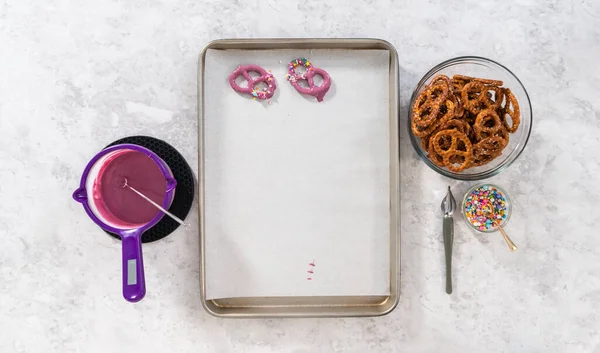 Flat lay. Dipping pretzels twists into melted chocolate to make mermaid pretzel twists.