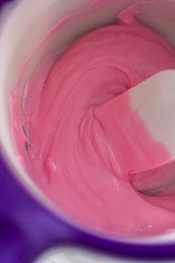 Panda şeklindeki kurabiyeler için çikolatalı fiyonk yapmak için şekerleme kabında pembe çikolata parçacıkları eritiyorum..