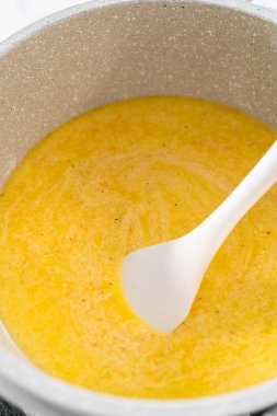 Peynirli makarna ve brokoli hazırlamak için tencerede peynir sosu pişirmek..